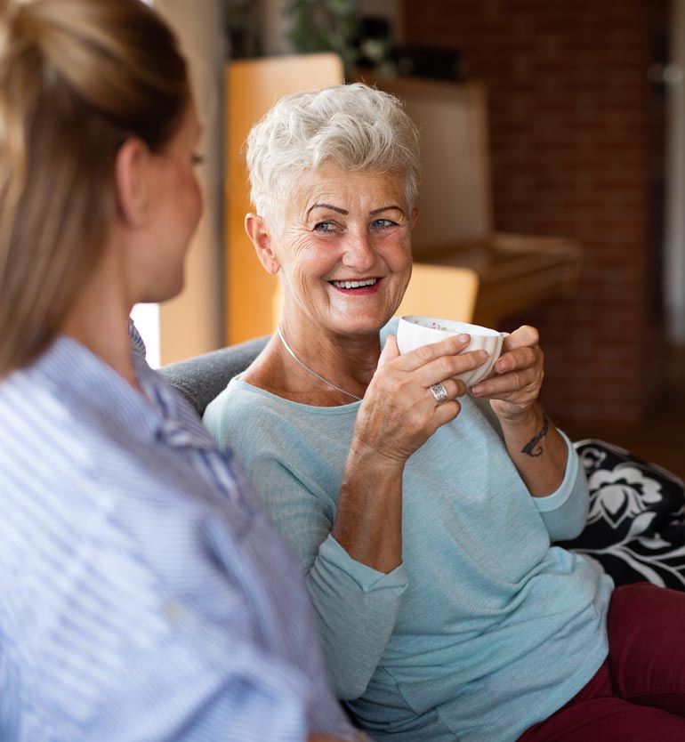 Senior woman enjoying a conversation and a cup of coffee with a team member.